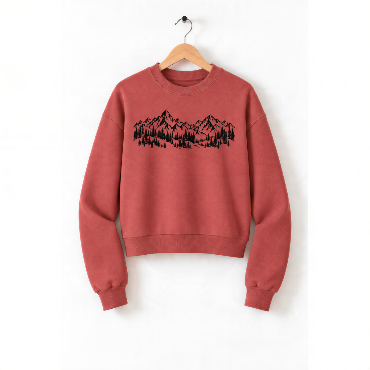 A red sweatshirt with a mountain landscape design printed on it, hanging on a wooden hanger.