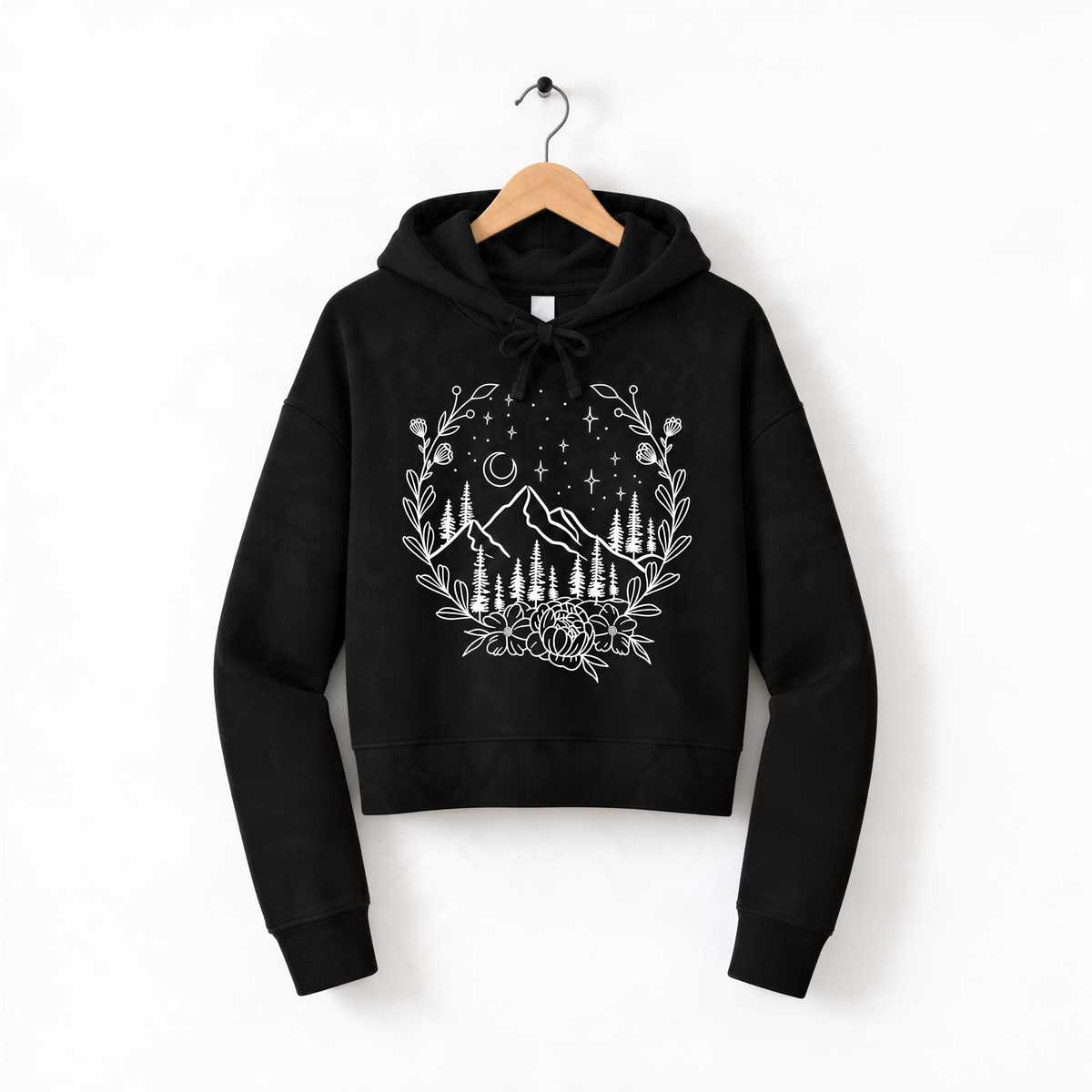 A black hoodie with a white graphic design depicting a mountain landscape with trees, flowers, and stars on a wooden hanger.