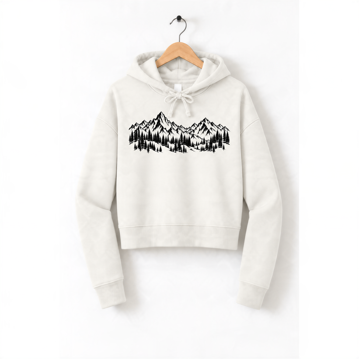 A white hoodie with a graphic design of mountains and trees printed on it, hanging on a wooden hanger.