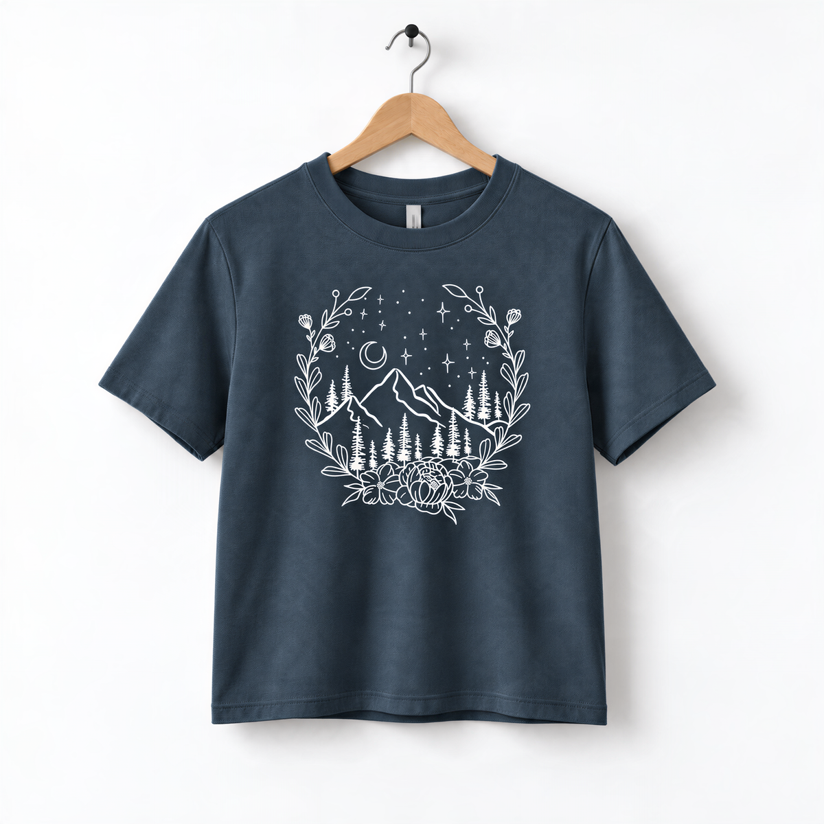 A navy blue t-shirt with a white graphic design depicting a mountain landscape with trees, flowers, and stars.
