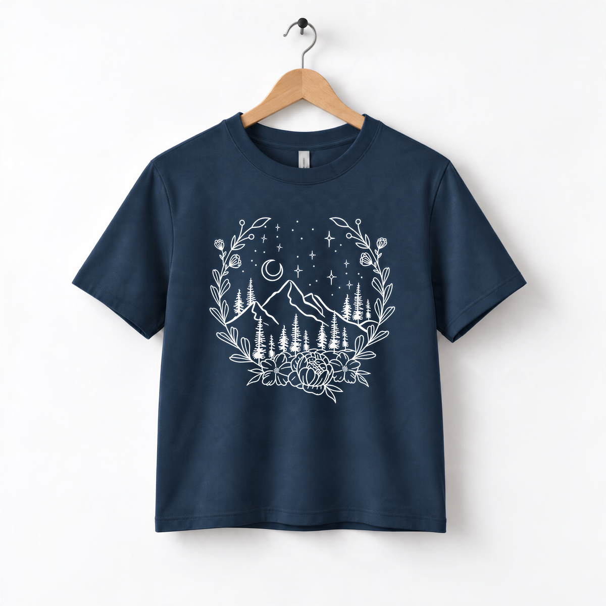A navy blue t-shirt with a white graphic design depicting a mountain landscape with trees, flowers, and a starry night sky.