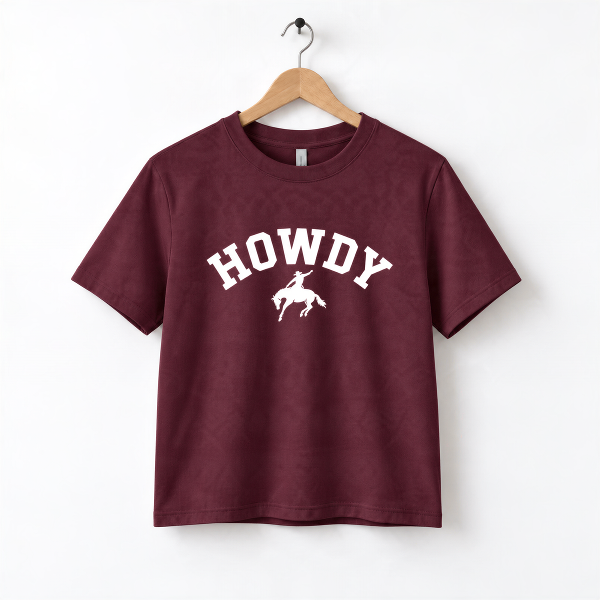 A burgundy-colored t-shirt with the text "HOWDY" printed on it, along with a graphic of a cowboy.