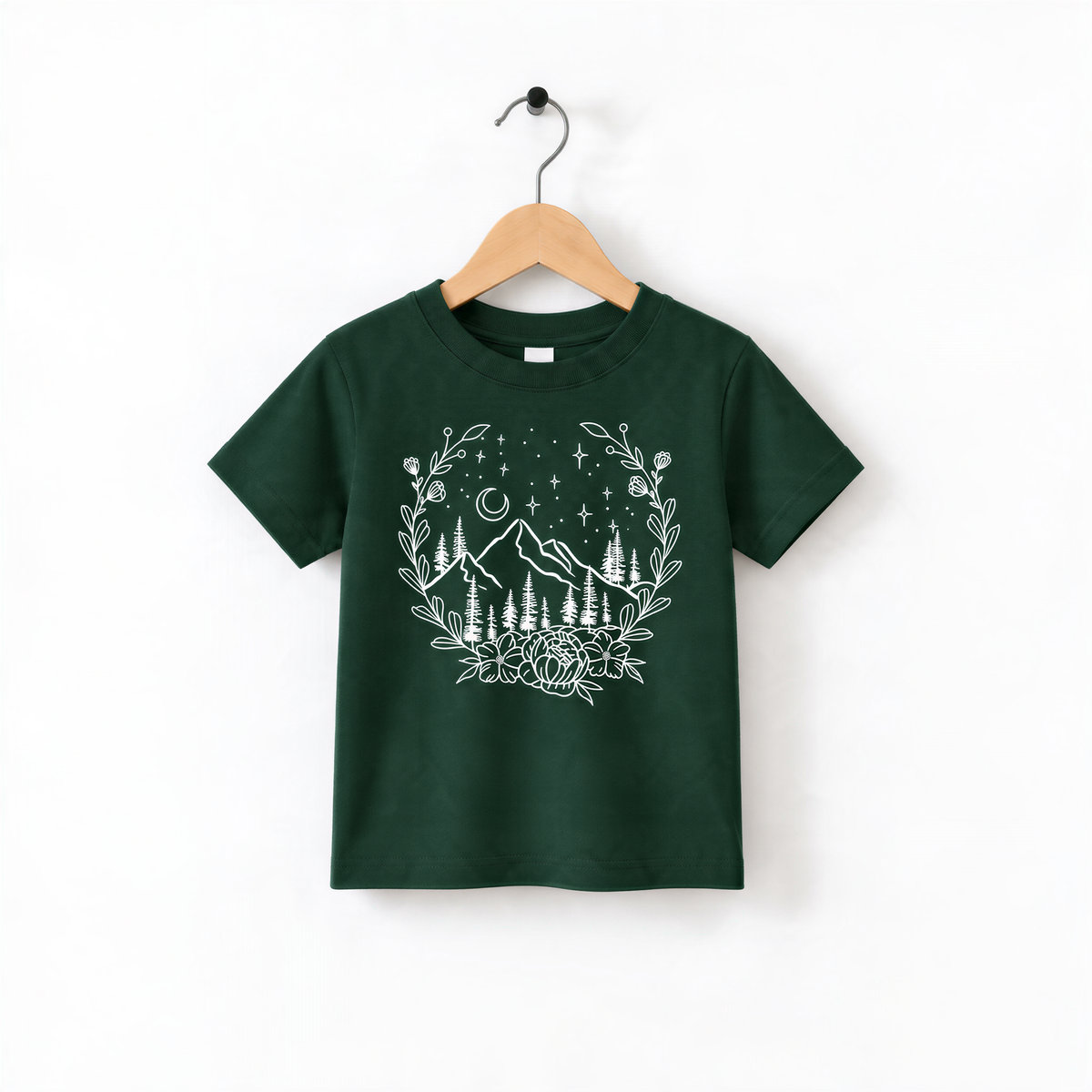 A green t-shirt with a white graphic design depicting a mountain landscape with trees, flowers, and stars.
