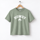 A green t-shirt with the word "HOWDY" printed on it, along with a silhouette of a cowboy.