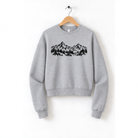 A gray sweatshirt with a graphic design of mountains and trees printed on it, hanging on a wooden hanger.