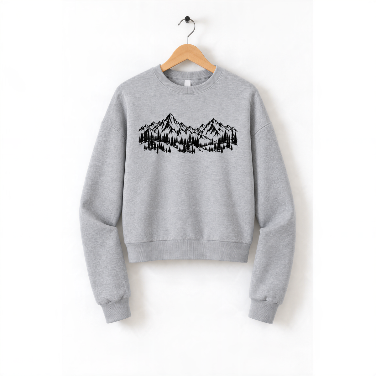 A gray sweatshirt with a graphic design of mountains and trees printed on it, hanging on a wooden hanger.
