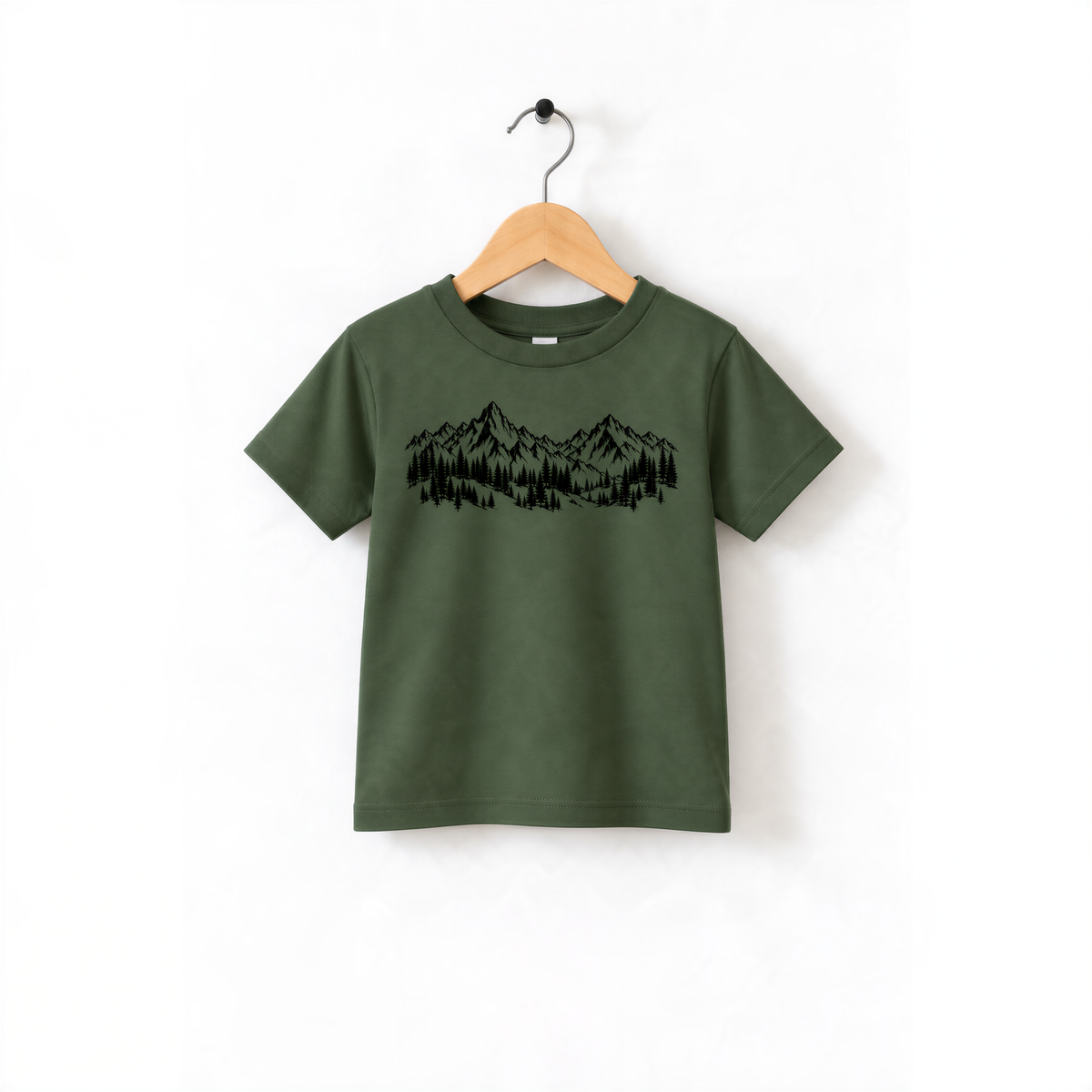 A green t-shirt with a graphic design of mountains and trees printed on it, hanging on a wooden hanger.