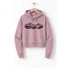 A pink hoodie with a graphic design of mountains and trees printed on it, hanging on a wooden hanger.