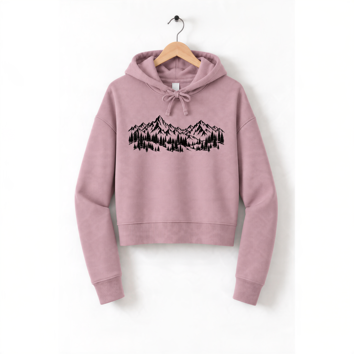 A pink hoodie with a graphic design of mountains and trees printed on it, hanging on a wooden hanger.