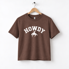 A brown t-shirt with the word "HOWDY" printed on it, along with a silhouette of a cowboy.