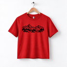 A red t-shirt with a graphic design of mountains and trees printed on it.