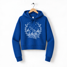 A blue hoodie with a white floral design on the front, hanging on a wooden hanger.