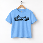 A light blue t-shirt with a graphic design of mountains and trees printed on it.