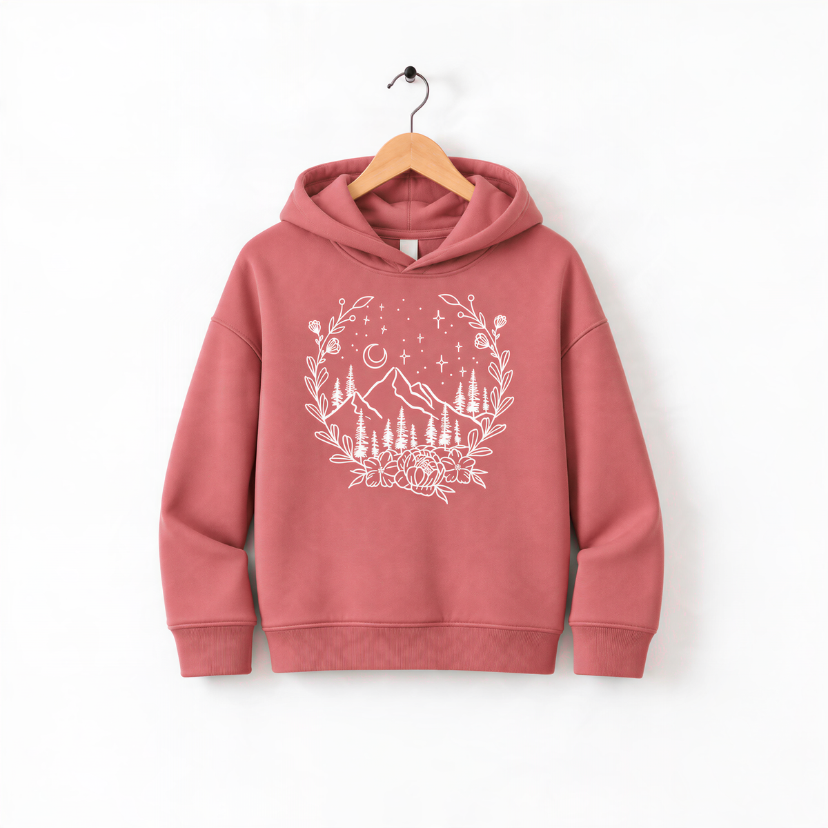 A pink hoodie with a white floral design and mountain landscape printed on it, hanging on a wooden hanger against a white background.