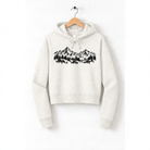 A white hoodie with a graphic design of mountains and trees printed on it, hanging on a wooden hanger.