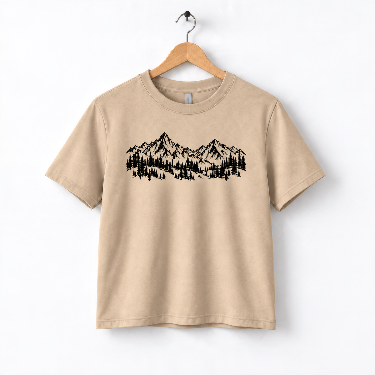 A beige t-shirt with a graphic design depicting a mountain range with trees.