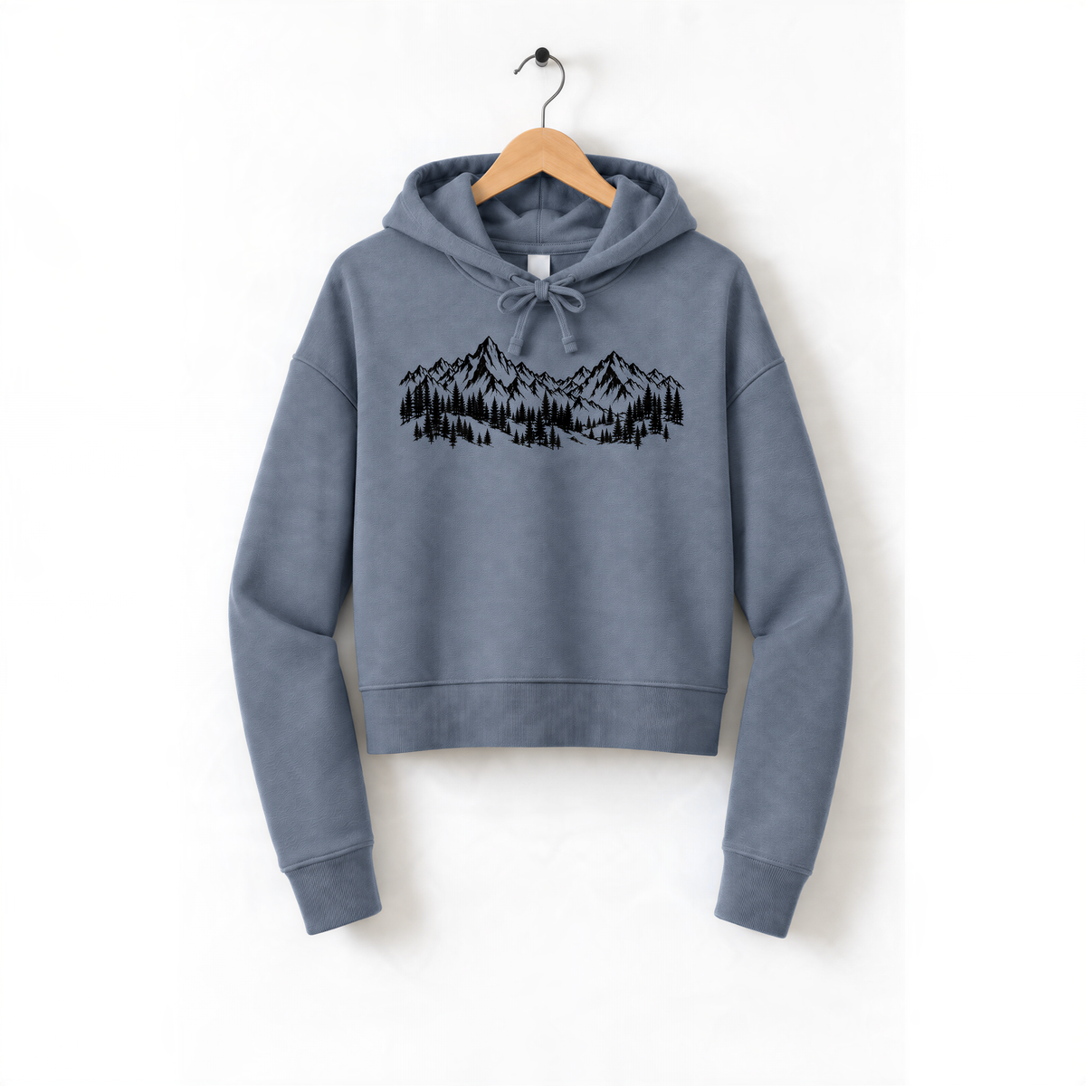 A gray hoodie with a graphic of mountains and trees printed on it, hanging on a wooden hanger.