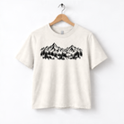 A white t-shirt with a graphic design depicting a mountain range with pine trees.