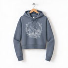 A gray hoodie with a white graphic design depicting a mountain landscape with trees, flowers, and a starry night sky.