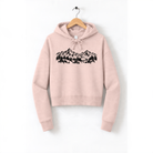 A pink hoodie with a graphic of a mountain range printed on it, hanging on a wooden hanger.