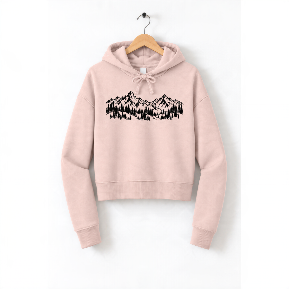 A pink hoodie with a graphic of a mountain range printed on it, hanging on a wooden hanger.