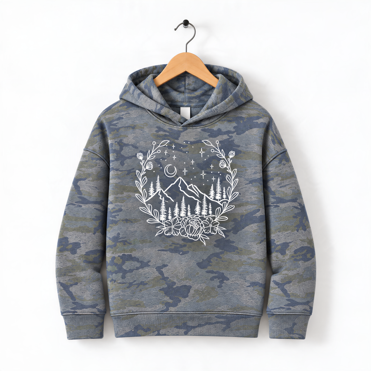 A camouflage hoodie with a white floral design on the front, hanging on a wooden hanger.