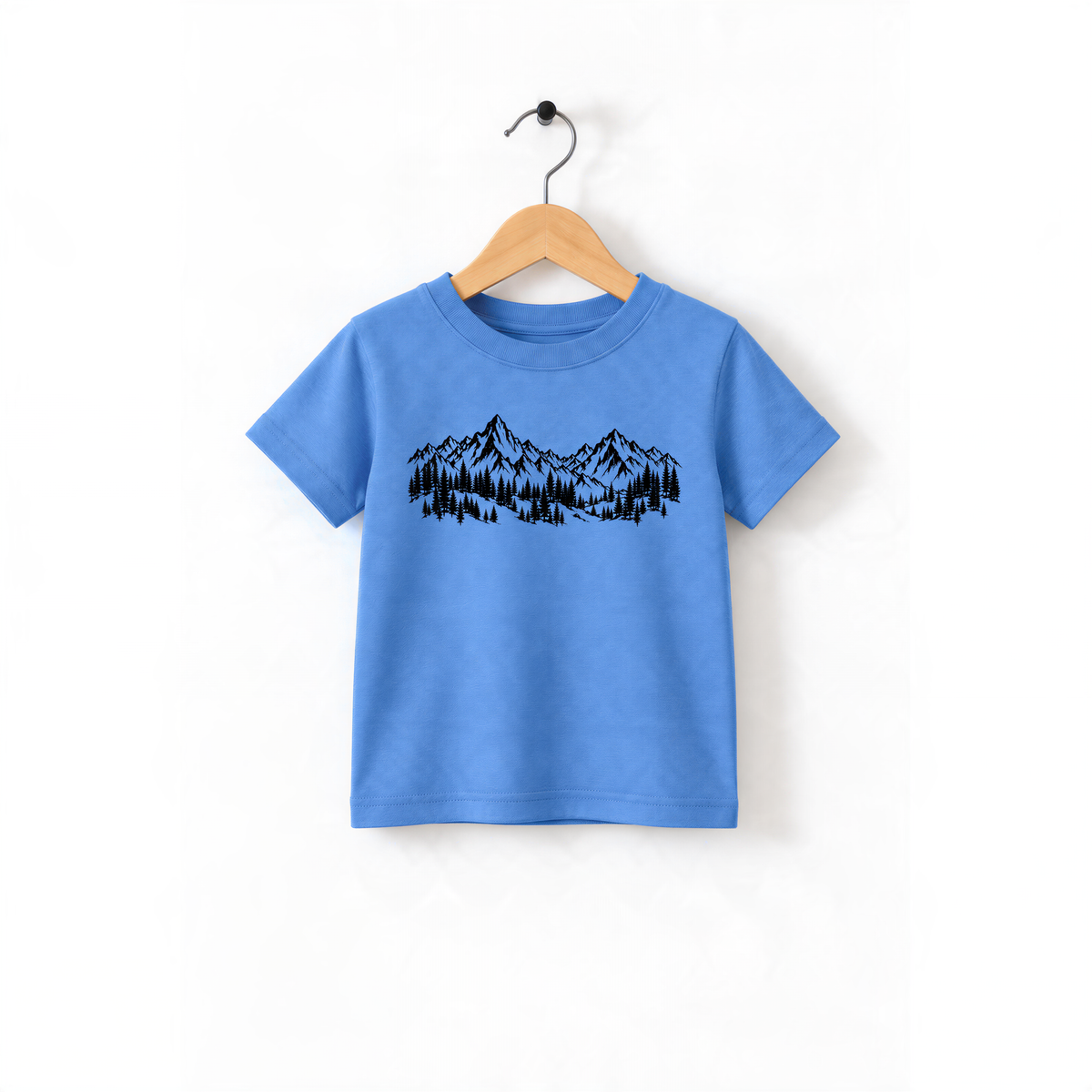 A blue t-shirt with a mountain landscape design printed on it, hanging on a wooden hanger.