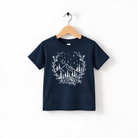 A navy blue t-shirt with a white graphic design depicting a mountain landscape with trees, flowers, and stars.