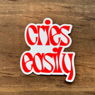 Red and white sticker with stylized text on a wooden surface