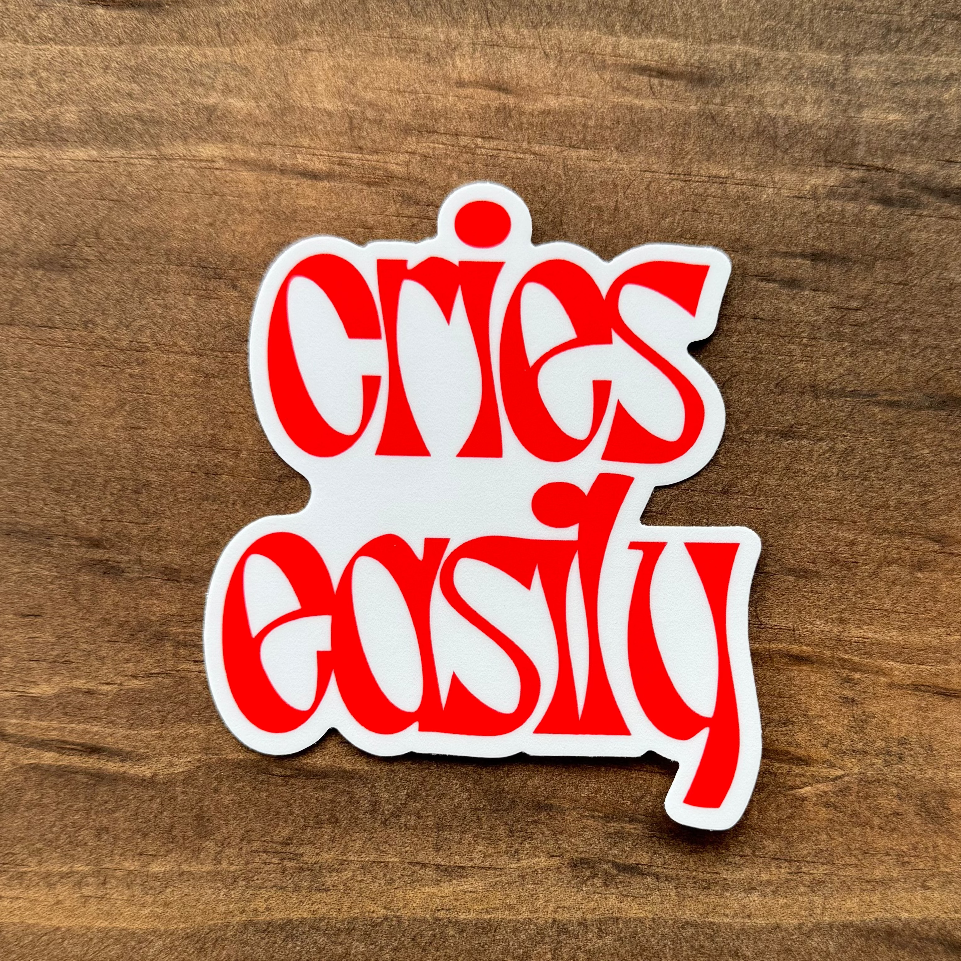 Red and white sticker with stylized text on a wooden surface