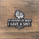 Sticker with text 'In memory of when I gave a shit' on a wooden surface