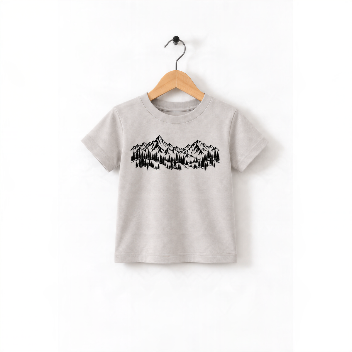 A gray t-shirt with a graphic design of mountains and trees printed on it, hanging on a wooden hanger.