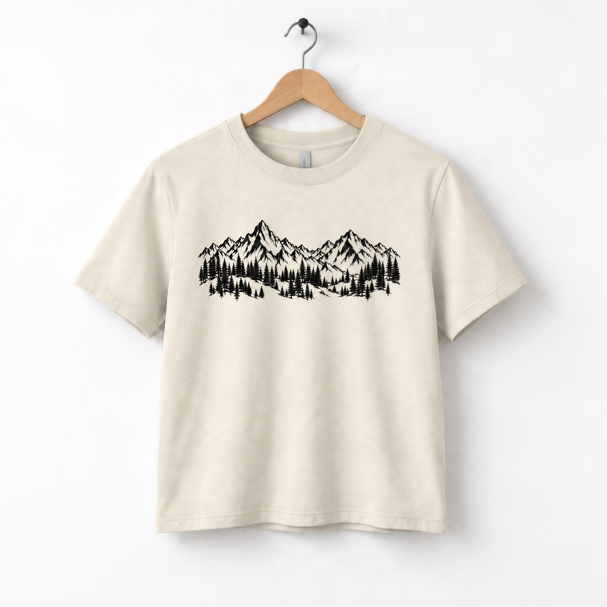 A beige t-shirt with a graphic design depicting a mountain range with pine trees.