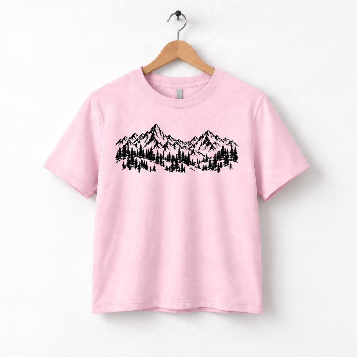 A pink t-shirt with a graphic design of mountains and trees printed on it.