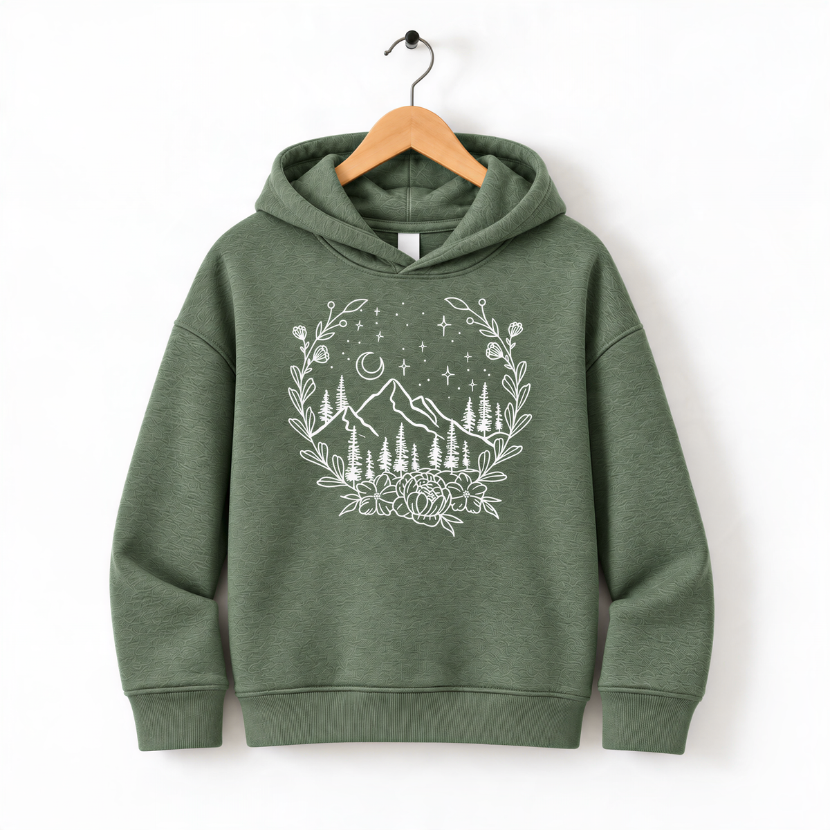 A green hoodie with a white graphic design depicting a mountain landscape with trees, flowers, and stars on a wooden hanger.