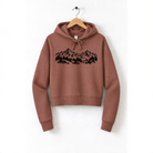A brown hoodie with a graphic design of mountains and trees printed on it, hanging on a wooden hanger.