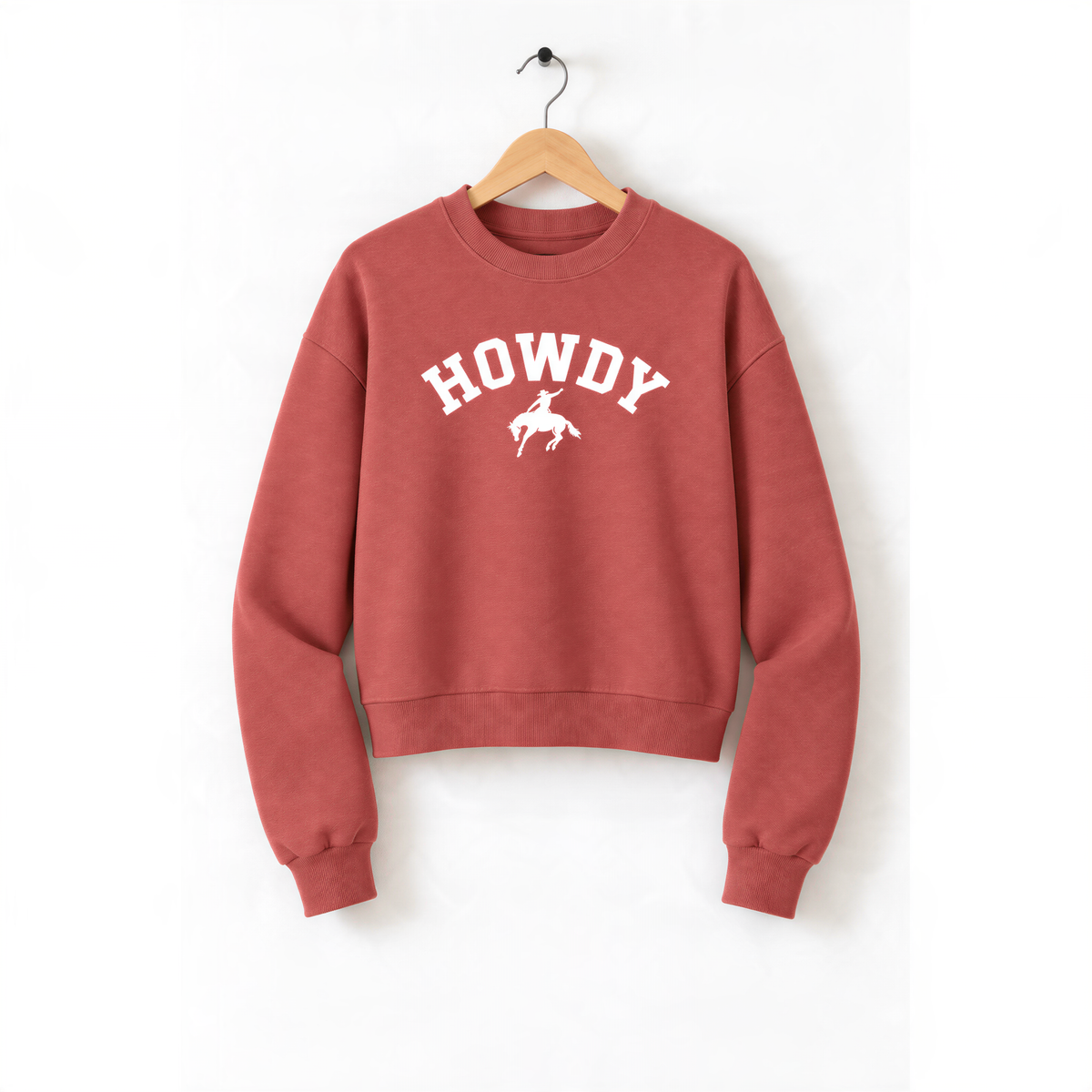A red sweatshirt with the word "HOWDY" printed on it, hanging on a wooden hanger.